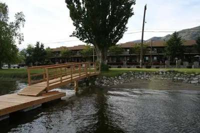 a wooden bridge over a river in front of a building at Casa Del Mila Oro Condo in Osoyoos