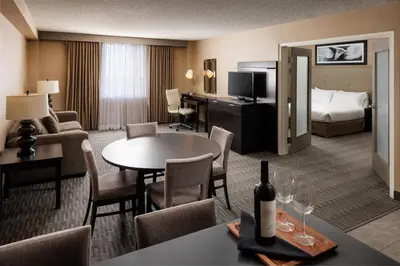 a hotel room with a bed and a table with a bottle of wine at Pomeroy Hotel & Conference Centre in Grande Prairie