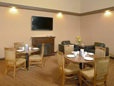 a room with tables and chairs and a flat screen tv at Coast Fraser Inn in Williams Lake