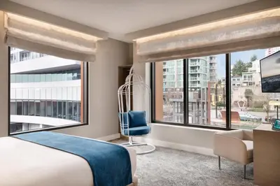 a bedroom with a bed and two large windows at Seaside Hotel North Vancouver in North Vancouver