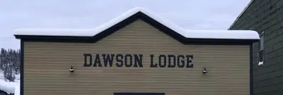 a sign on the side of a building with snow on it at Dawson Lodge in Dawson City