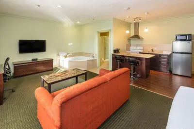 a living room with an orange couch and a kitchen at Quality Inn & Suites in Whitecourt