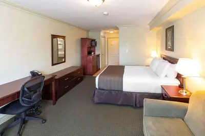 a hotel room with a bed and a desk and a chair at Quality Inn & Suites in Whitecourt