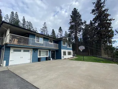 a blue house with a balcony and a garage at The Blue House Bed and Breakfast in Lake Country