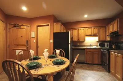 a kitchen with a table with chairs and a black refrigerator at Rainbow Suites by Whistler Retreats in Whistler