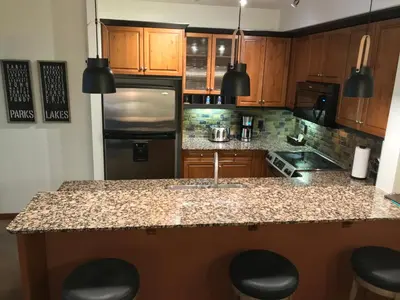 a kitchen with wooden cabinets and a granite counter top at Luxurious & Spacious Mountain Retreat in Canmore