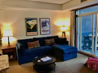 a living room with a blue couch and a table at Luxurious & Spacious Mountain Retreat in Canmore