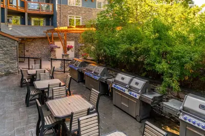 an outdoor patio with tables and chairs and a grill at Luxurious & Spacious Mountain Retreat in Canmore