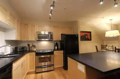 a kitchen with wooden cabinets and a black counter top at Villas Snowberry by Whistler Retreats in Whistler