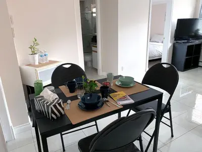 a dining room table with chairs and a black table with plates and dishes at Perfect Location - Entire Suite Private Entrance with private bathroom & living room - 5 Mins Walk to Skytrain & Restaurant & Banks, 2 Stops To Metrotown, 5 Stops To Downtown in Vancouver