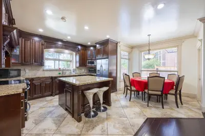 a kitchen with wooden cabinets and a table and chairs at Francis Home Hotel \u798f\u6765\u987a\u5bb6\u5ead\u5bbe\u9986 in Richmond