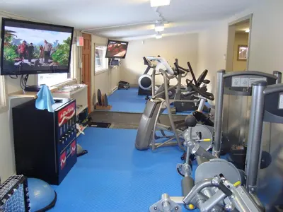 a fitness room with a gym with a flat screen tv at YPC Fitness & Accomodations in Invermere