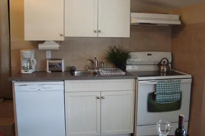 a kitchen with white cabinets and a sink and a dishwasher at YPC Fitness & Accomodations in Invermere