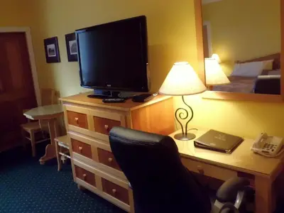 a hotel room with a desk with a tv and a chair at Park Place Lodge in Fernie