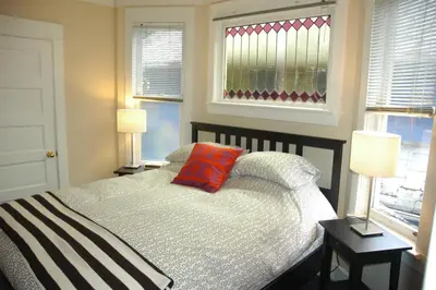 a bedroom with a bed with a red pillow on it at Douglas Guest House in Vancouver