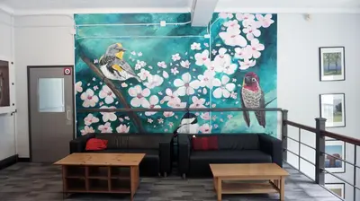 a living room with a couch and a painting of birds at HI Vancouver Jericho Beach - Hostel in Vancouver