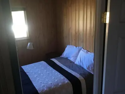 a small bed in a room with a window at Barney’s Lakeside Resort in Puntzi Lake