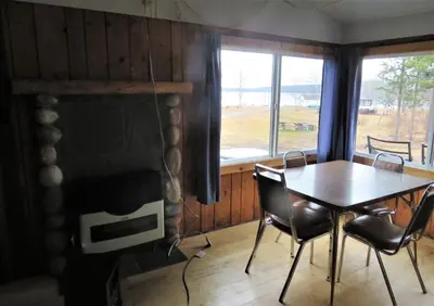 a dining room with a table and a fireplace at Barney’s Lakeside Resort in Puntzi Lake