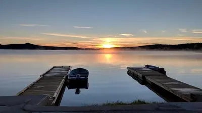 two boats are docked at a dock on a lake at Barney’s Lakeside Resort in Puntzi Lake