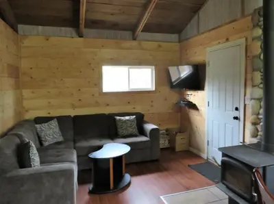 a living room with a couch and a tv at Barney’s Lakeside Resort in Puntzi Lake