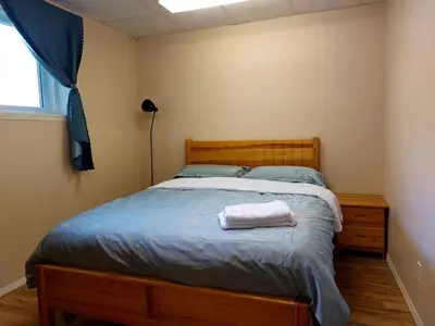 a bedroom with a bed with a wooden headboard and a window at Green Village in Calgary