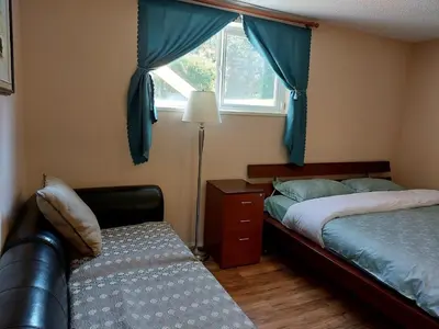 a bedroom with two beds and a window and a chair at Green Village in Calgary
