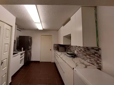 a kitchen with white cabinets and a brick wall at Green Village in Calgary