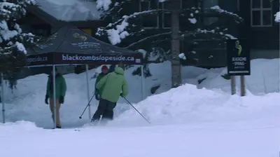 two people are skiing down a snow covered street at Blackcomb Springs Suites by CLIQUE in Whistler