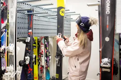a woman taking a picture of a group of skis at Blackcomb Springs Suites by CLIQUE in Whistler