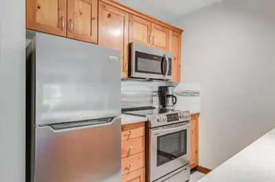 a kitchen with stainless steel appliances and wooden cabinets at Blackcomb Springs Suites by CLIQUE in Whistler
