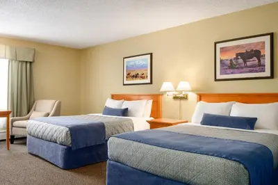 a hotel room with two beds and a chair at Travelodge by Wyndham Edson in Edson