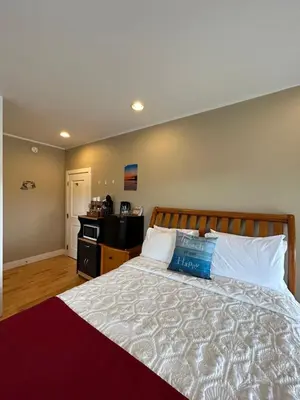 a bedroom with a bed with a blue pillow on it at Pacific Rim Guest Lodge - Adults Only in Ucluelet