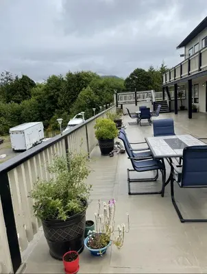 a balcony with tables and chairs and potted plants at Pacific Rim Guest Lodge - Adults Only in Ucluelet