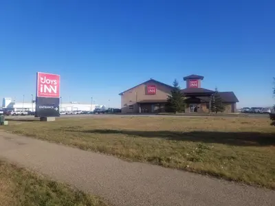 a building with a sign in front of a field at Joys Inn Innisfail, AB in Innisfail