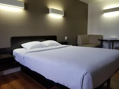 a bedroom with a large white bed and a chair at Joys Inn Innisfail, AB in Innisfail