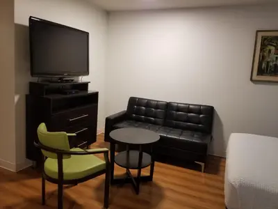 a living room with a couch and a table and a tv at Joys Inn Innisfail, AB in Innisfail