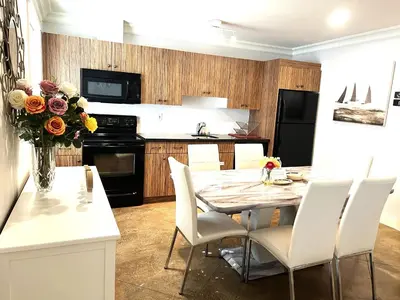 a kitchen with a table with white chairs and a vase of flowers at Hannah's Heavenly Home in Surrey