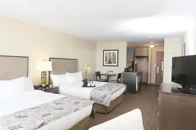 a hotel room with two beds and a flat screen tv at Pomeroy Inn & Suites at Olds College in Olds