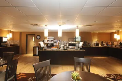 a restaurant with tables and chairs and a counter at Pomeroy Inn & Suites at Olds College in Olds