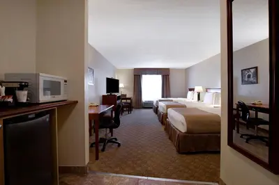 a hotel room with two beds and a desk at Days Inn by Wyndham Dawson Creek in Dawson Creek