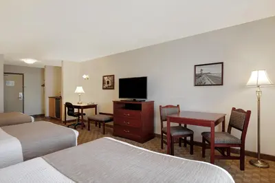 a hotel room with two beds and a desk and a television at Days Inn by Wyndham Dawson Creek in Dawson Creek