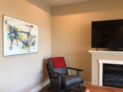 a chair sitting next to a fireplace with a television at Botany Bay by Eagle Reach Properties in Port Renfrew