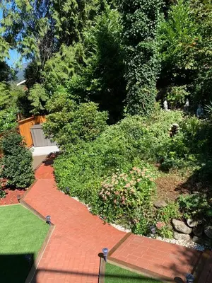 a garden with a red brick walkway and bushes at Beautiful Two Bedroom Suite in North Vancouver