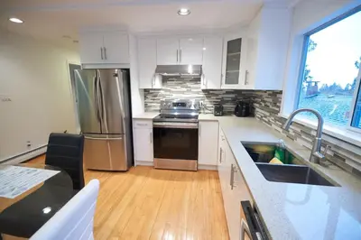 a kitchen with white cabinets and stainless steel appliances at Beautiful Two Bedroom Suite in North Vancouver