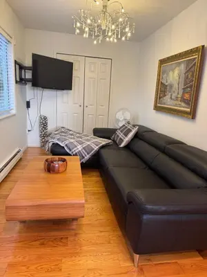 a black leather couch in a living room with a table at Beautiful Two Bedroom Suite in North Vancouver
