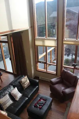 a living room with leather furniture and large windows at Woodhaven # 8 in Sun Peaks in Sun Peaks