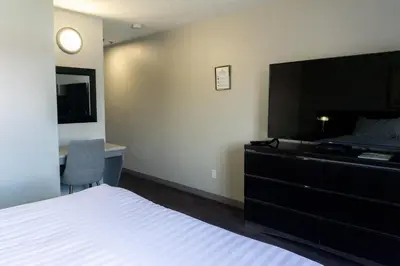 a bedroom with a bed and a dresser with a television at The Baker Hotel in Cranbrook