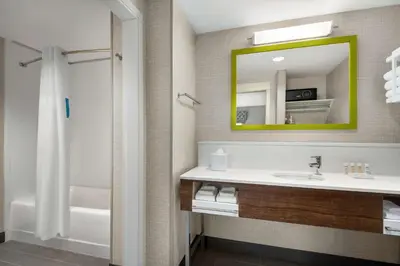 a bathroom with a sink and a mirror and a tub at Hampton Inn & Suites Kelowna, British Columbia, Canada in Kelowna