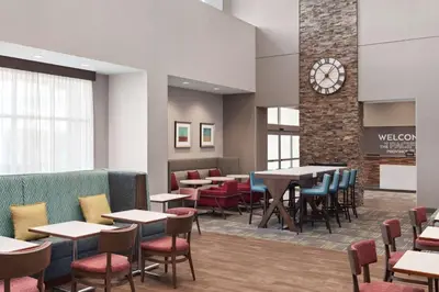a dining room with tables and chairs and a clock at Hampton Inn & Suites Kelowna, British Columbia, Canada in Kelowna