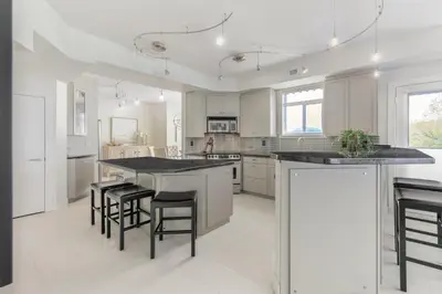 a white kitchen with a large island with black counter tops at Kelowna Discovery in Kelowna